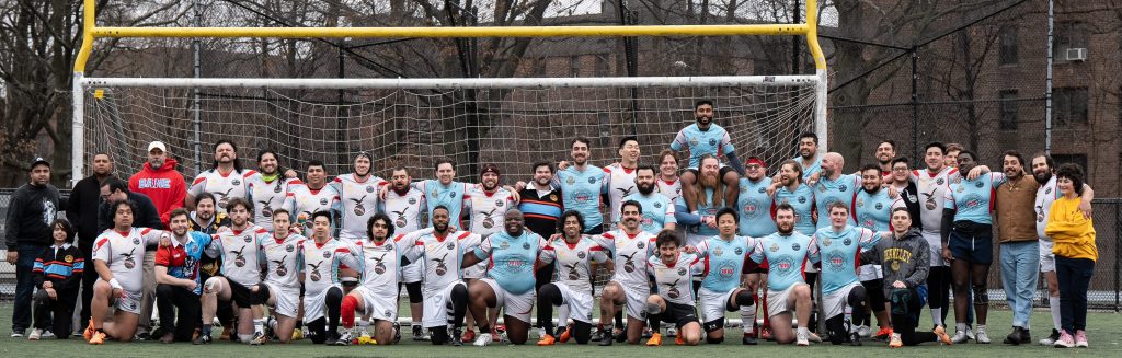 Queens Rugby poses after an intersquad scrimmage, with some teams wearing white jerseys and others blue jerseys.